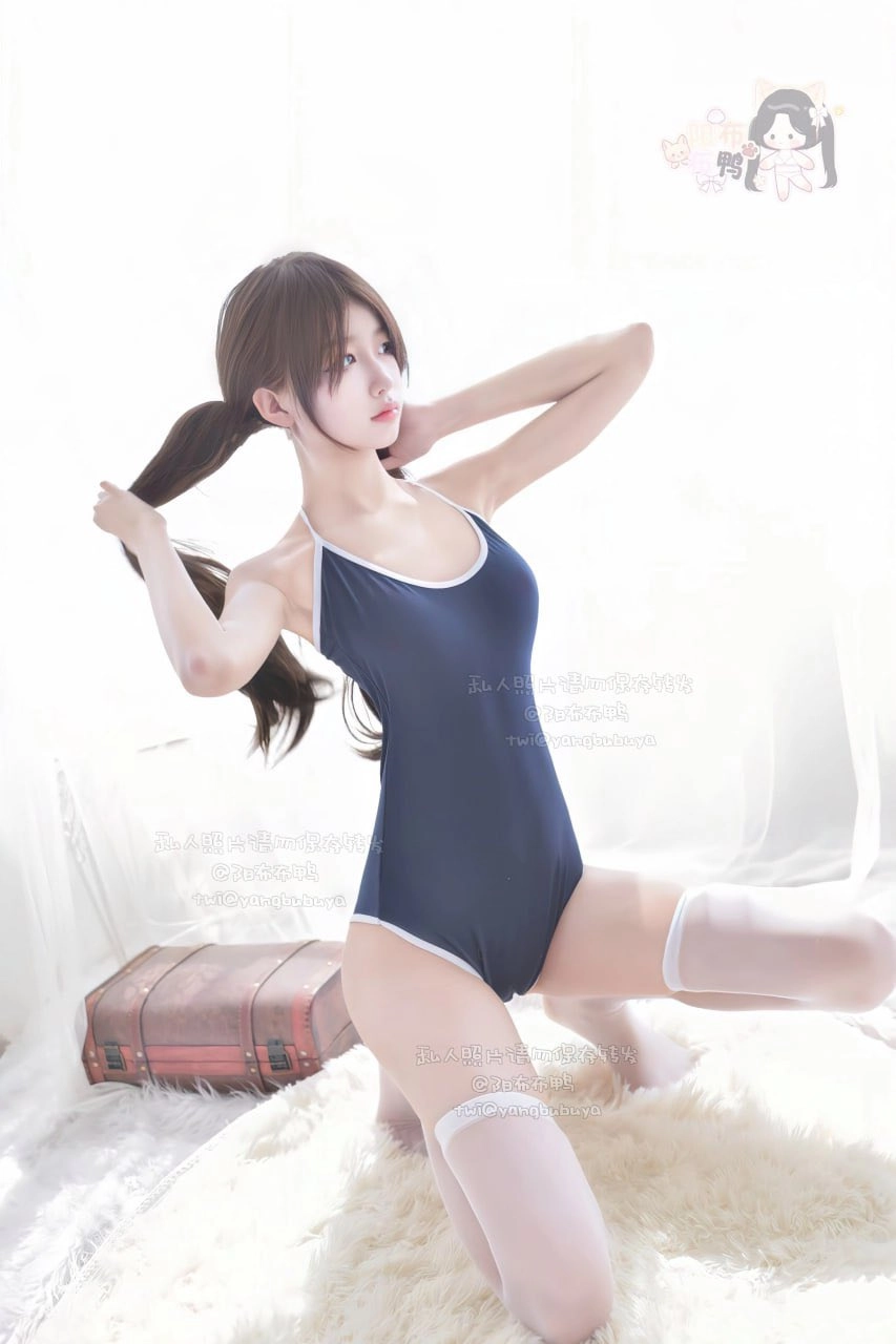 穿蓝色泳衣的女人坐在白色的地毯上。