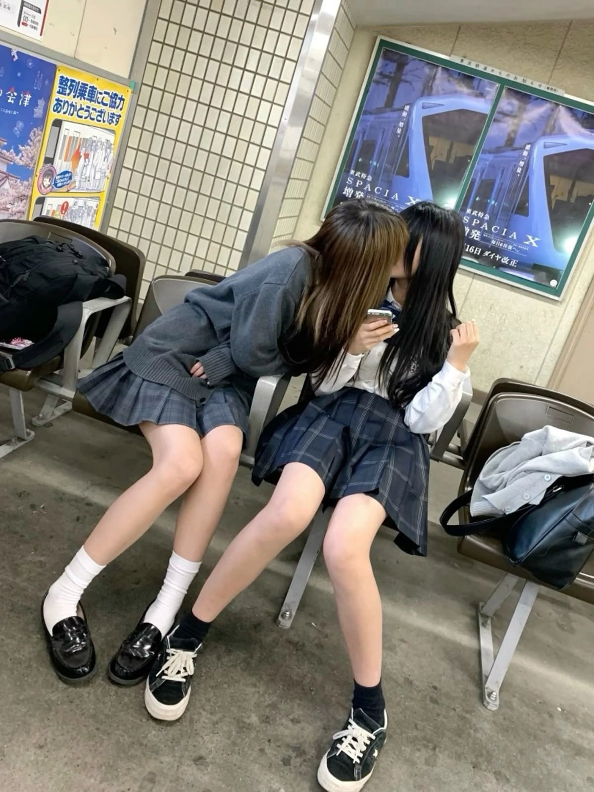 两个女孩坐在凳子上,其中一个接吻了另一个。