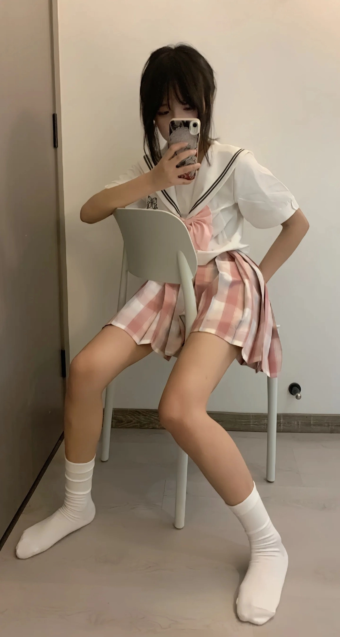 穿白色衬衫和粉红色裙子的女孩坐在椅子上。
