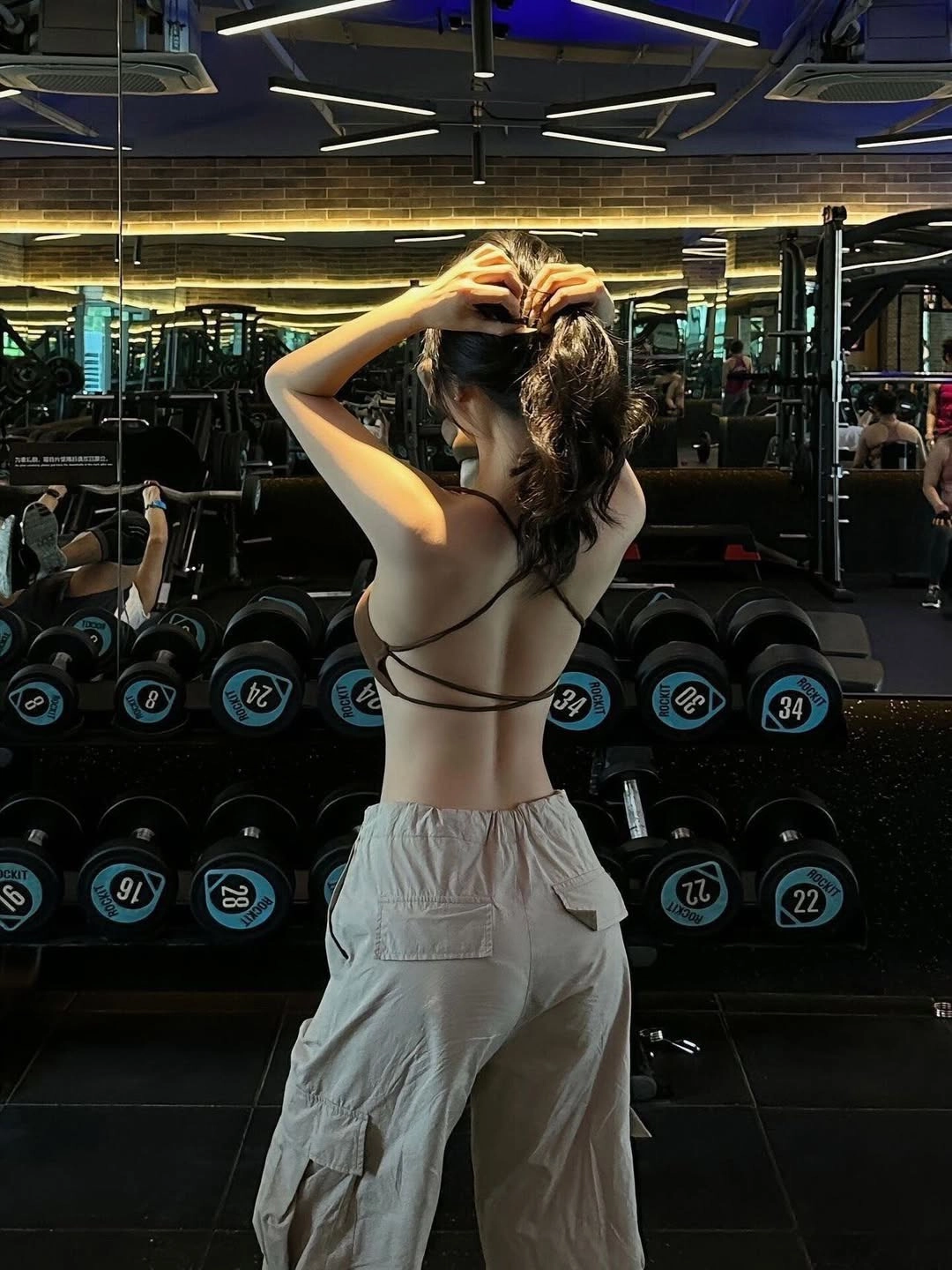 女人在健身房背转。