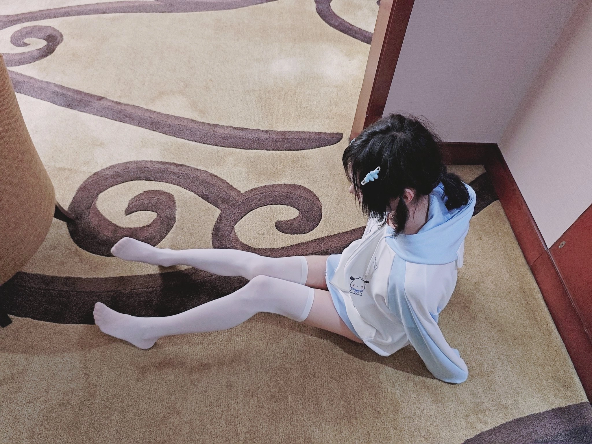 穿着白色裤子和白色袜子的女孩坐在地板上。