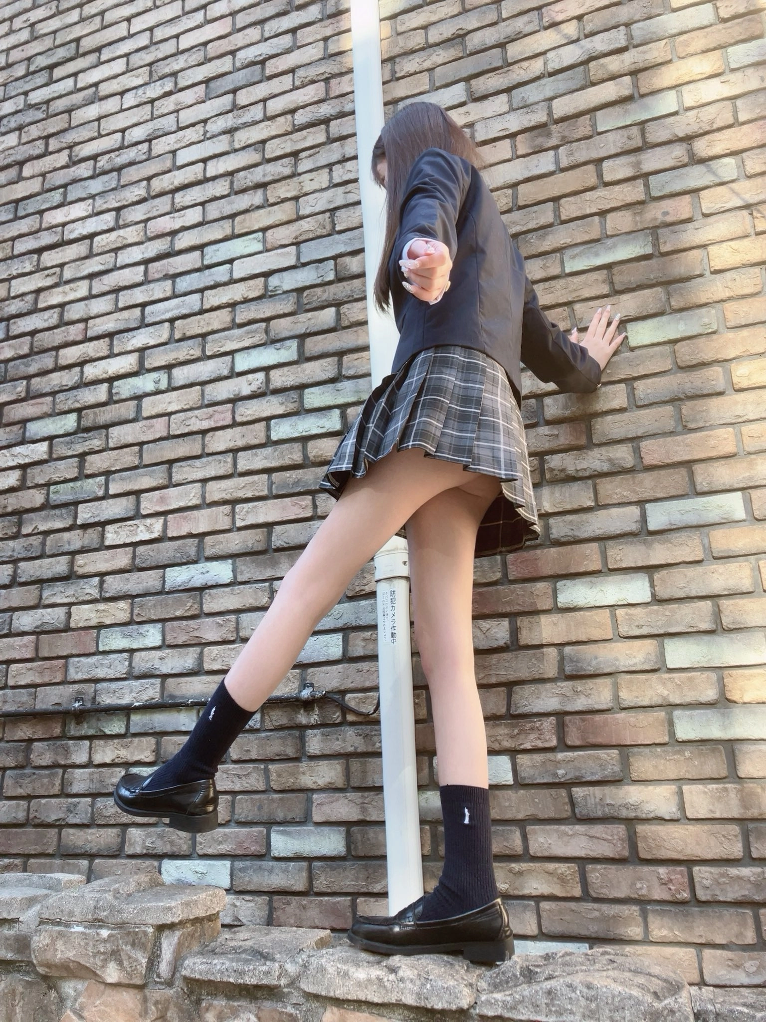 穿着裙子和黑色的鞋子的女人爬上一个极。