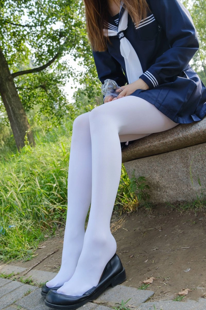 穿着蓝色裙子和白色袜子的女孩坐在一个步骤上。