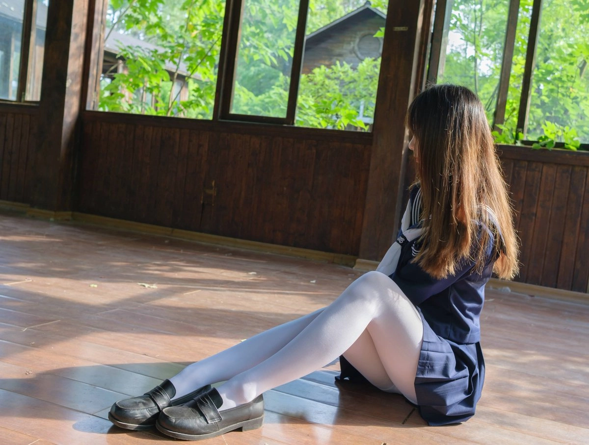 穿着蓝色裙子和白色袜子的女孩坐在一个步骤上。