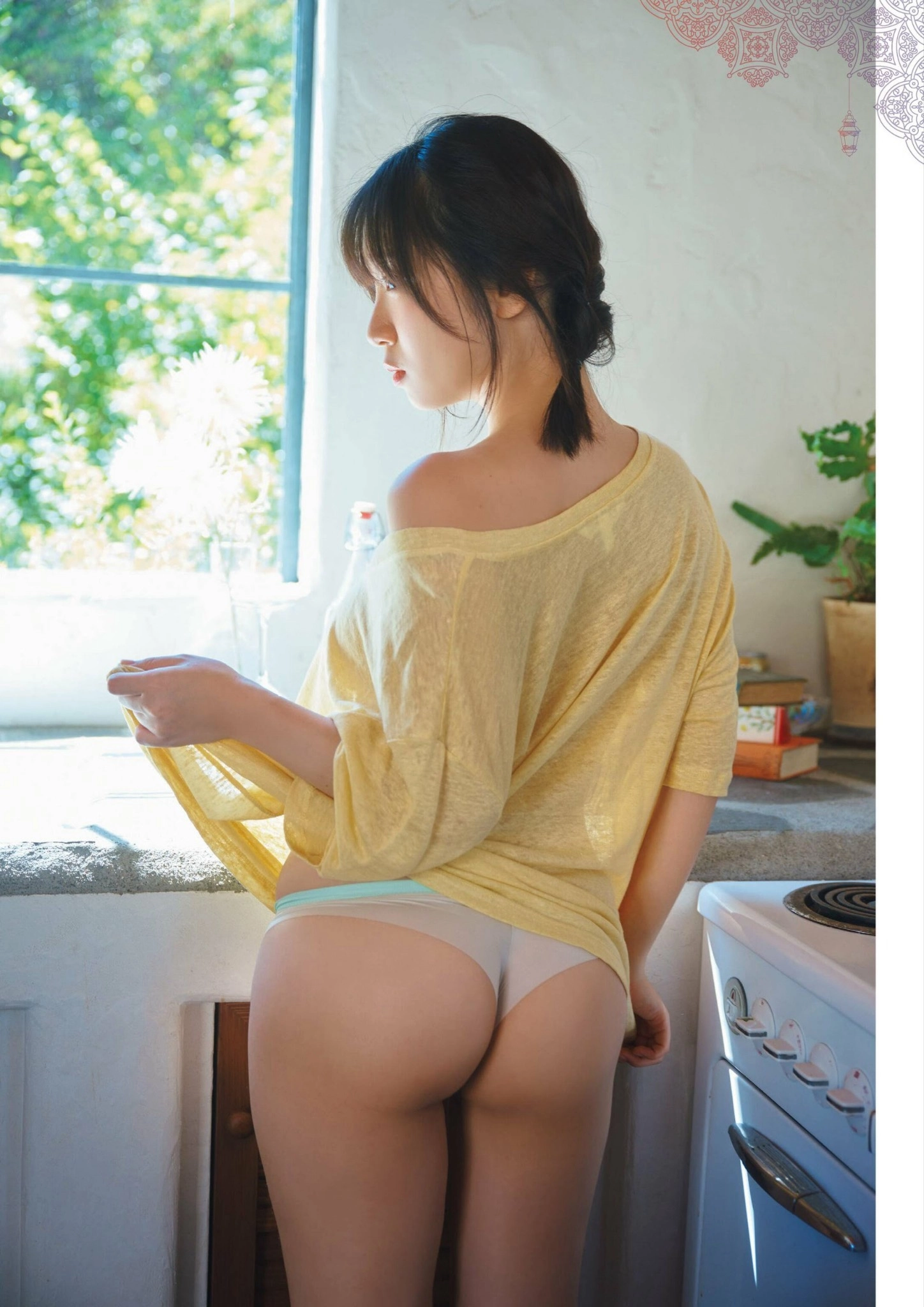 穿着黄色衬衫和白裤子的女人站在厨房里。