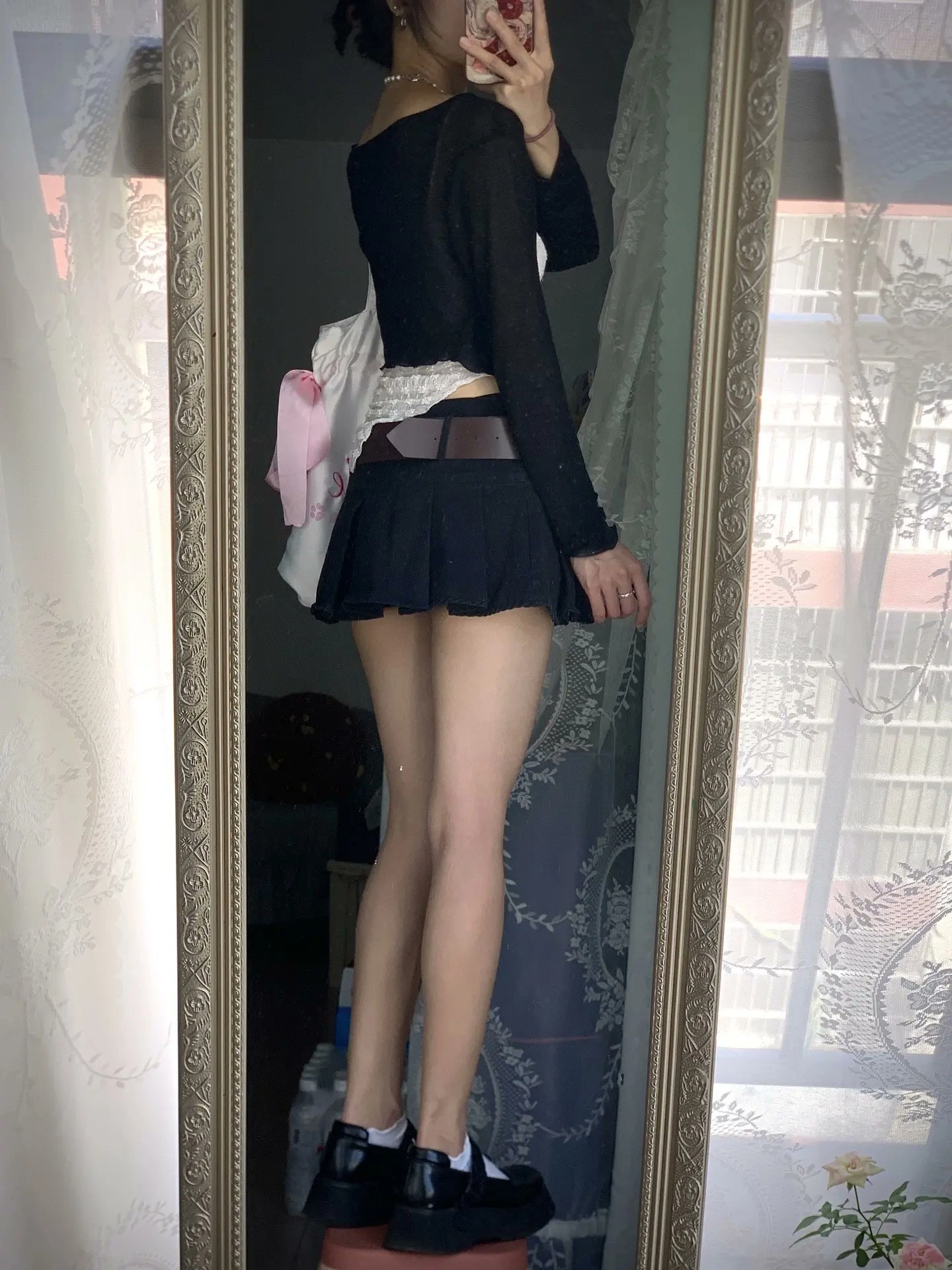穿着黑色衬衫和裙子的女人站在镜子前。