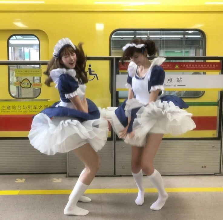 两个女人穿着女仆服装在火车前跳舞。