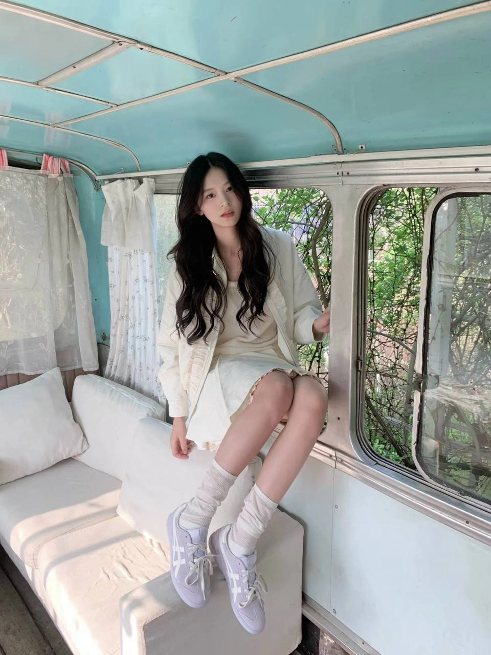 女人坐在一个凳子上,戴着一件白色衬衫和白袜子。