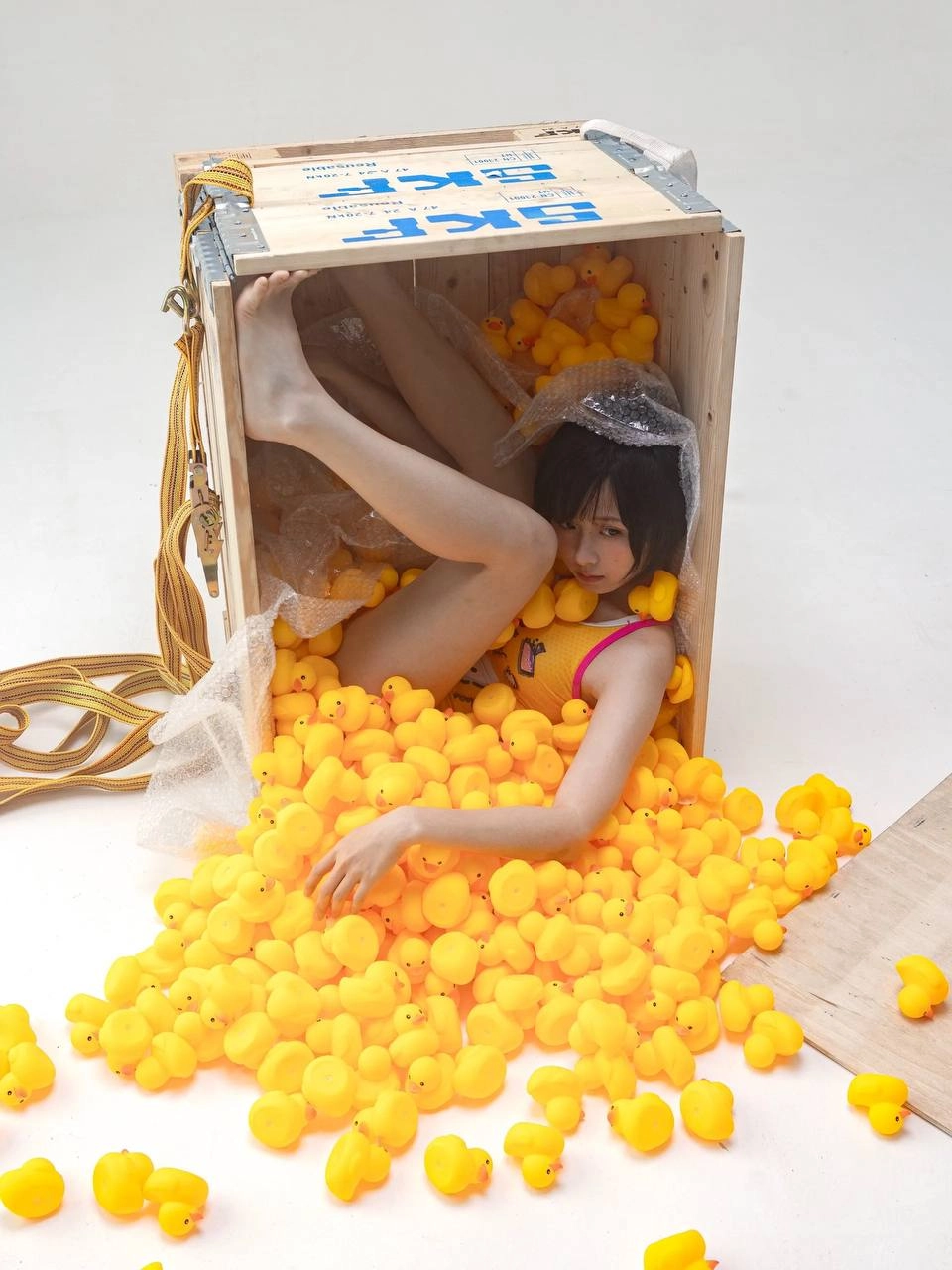 女孩在一个装满黄橡胶鸭子的盒子里。
