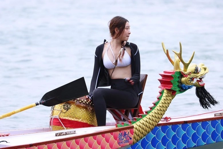 一位穿着蓝色衬衫和帽子的女人坐在椅子上,发出和平的信号。