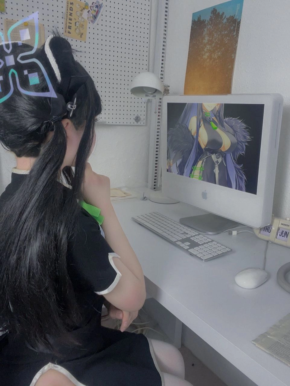 女孩坐在一张桌子上,一台电脑屏幕在她面前。