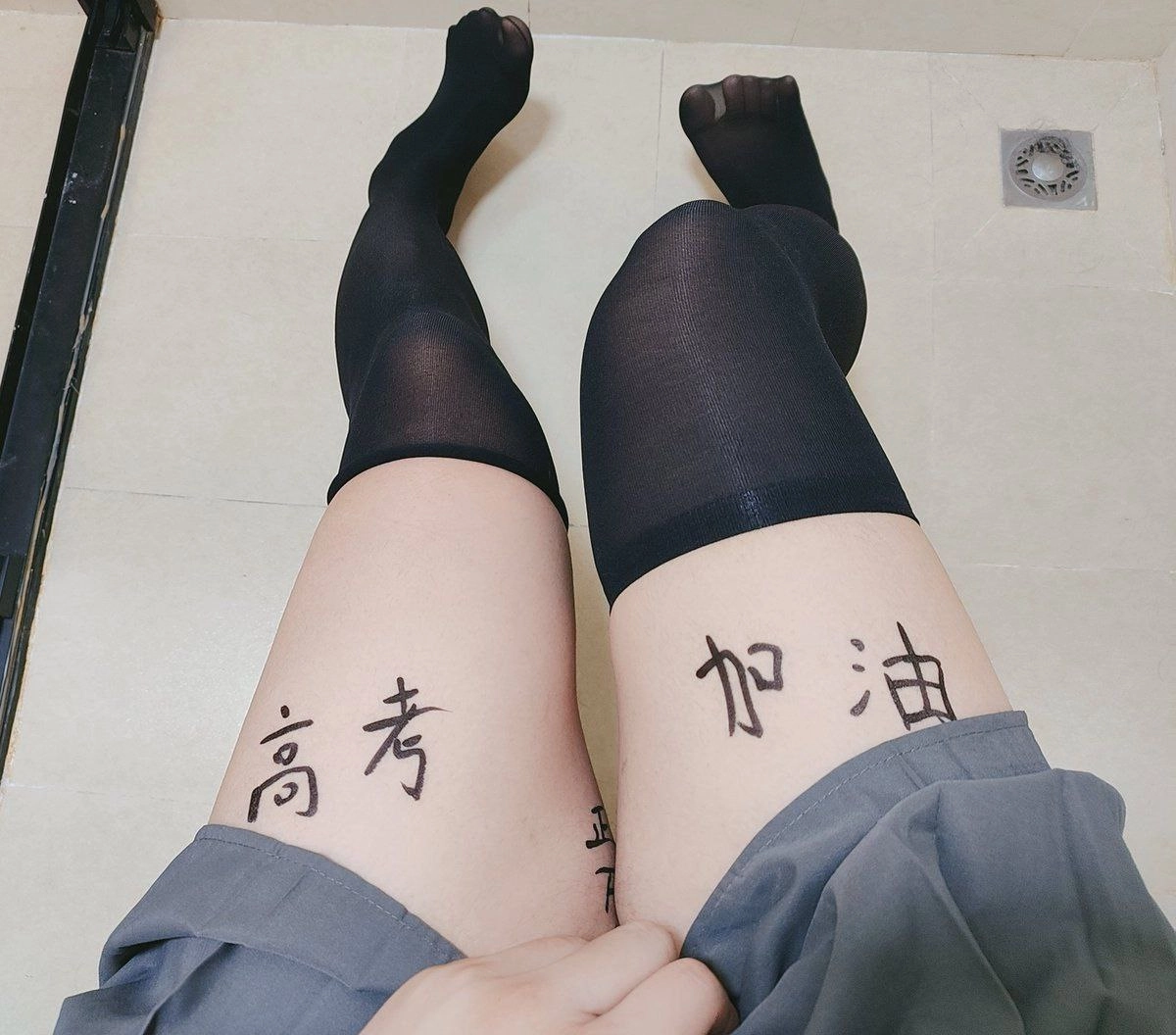 穿着黑色袜子和灰色裙子的女人,她的腿上有中国字符纹身。