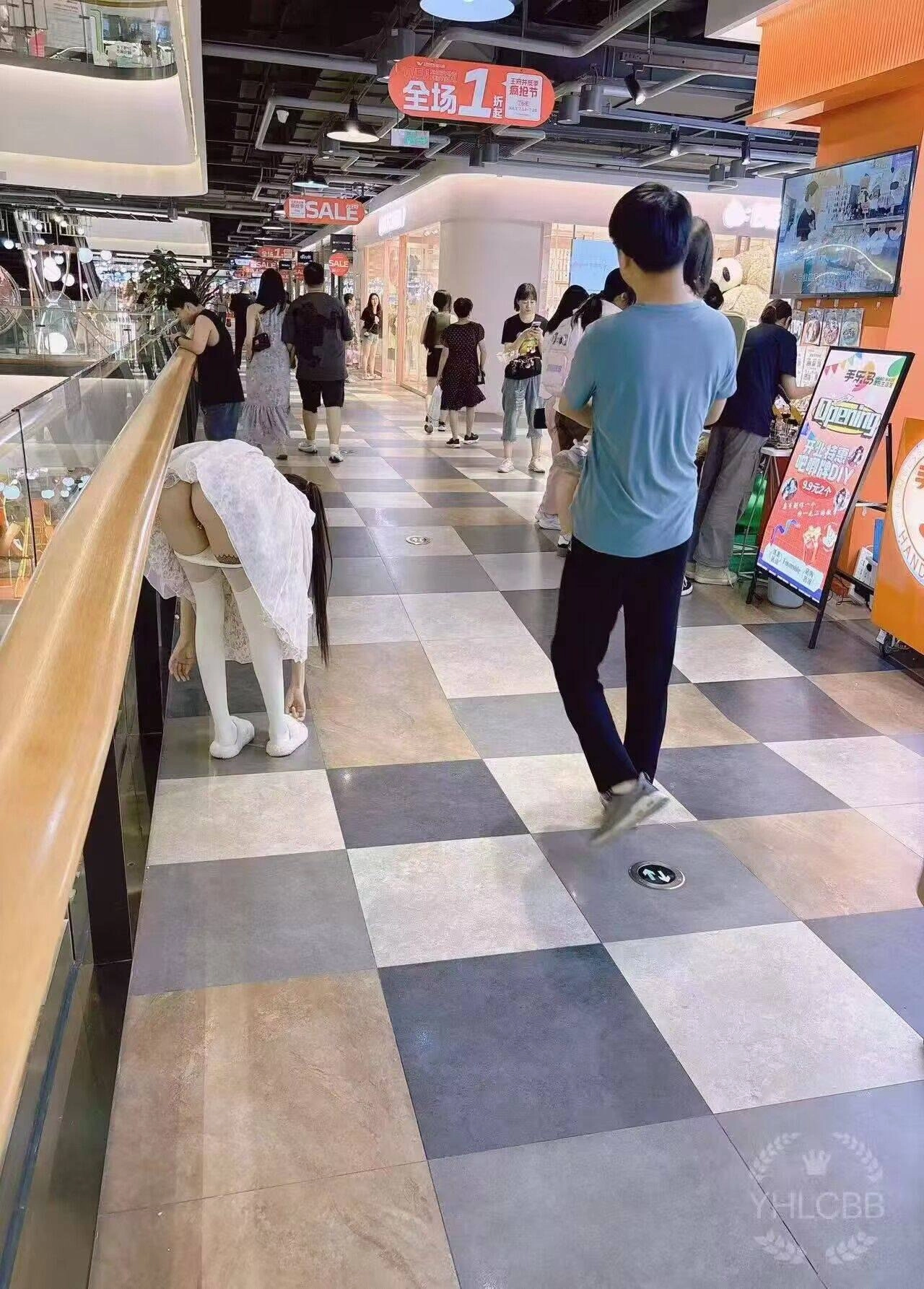 女人在一个商场上弯曲着她的裙子。