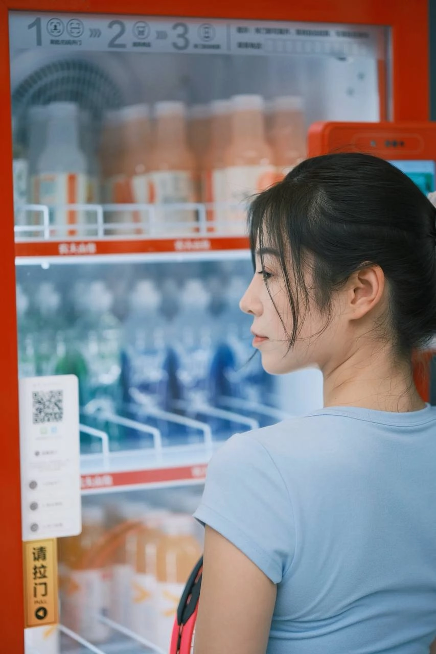 一位穿着白色衣服的女人站在一台售货机前。