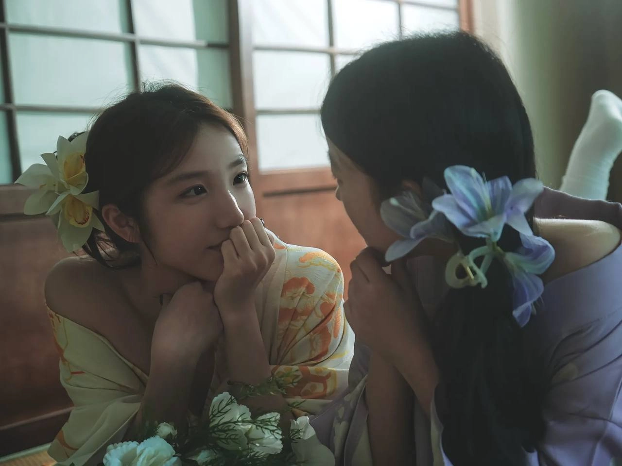 两位女士戴着吉莫诺坐在一张椅子上。