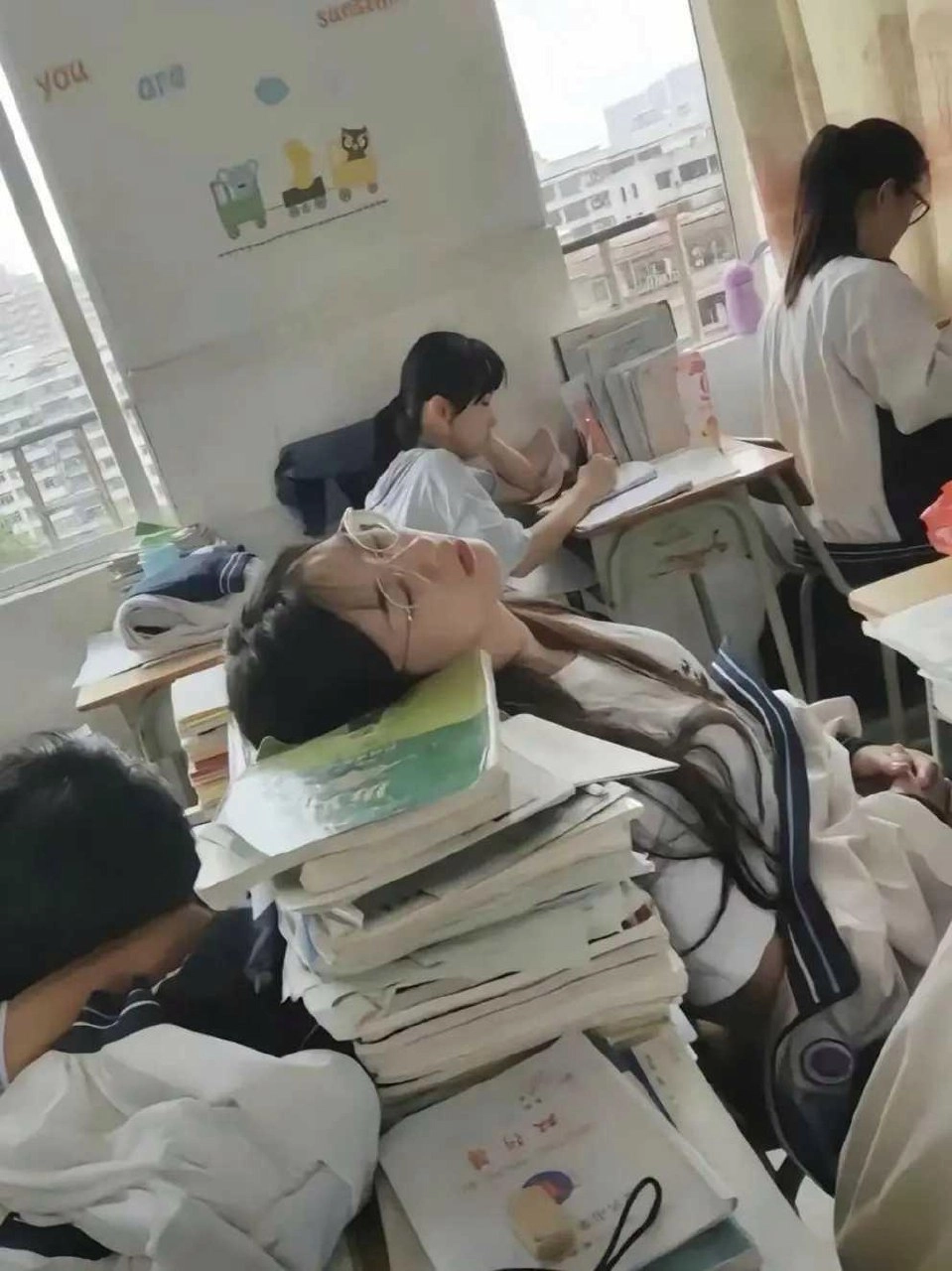 戴眼镜的女孩睡在一堆书上。