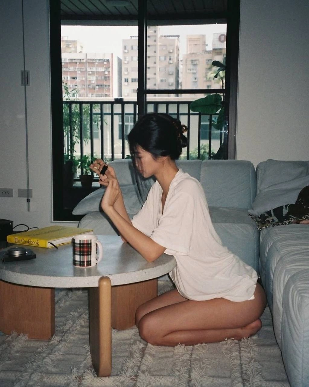 穿白衬衫的女人坐在沙发上,拿着手机。