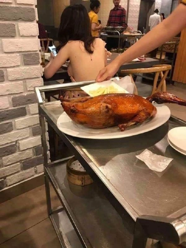 女人坐在一张桌子上,她面前有一盘食物。